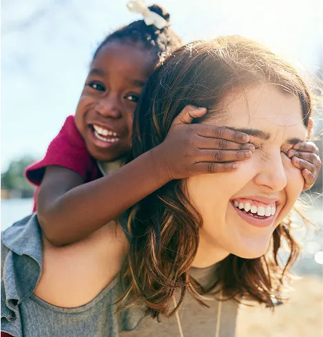Young student playfully hugging their smiling teacher on piggyback.