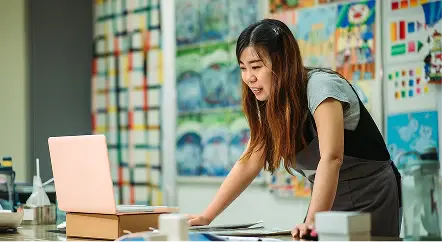Educator working at a laptop in a classroom.